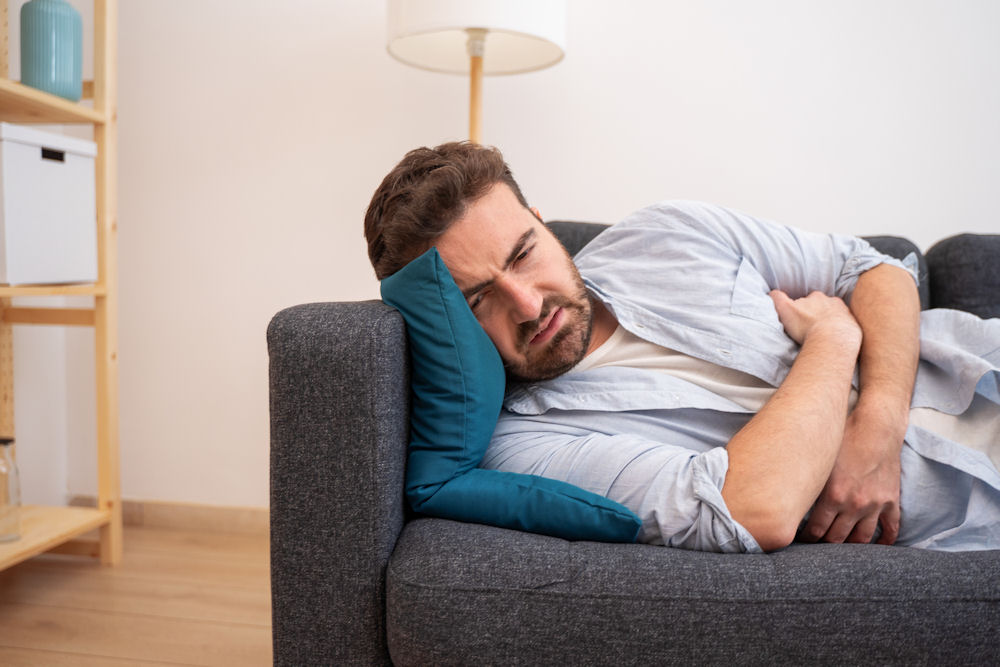 Man lying on a couch feeling sick due to alcohol poisoning effects