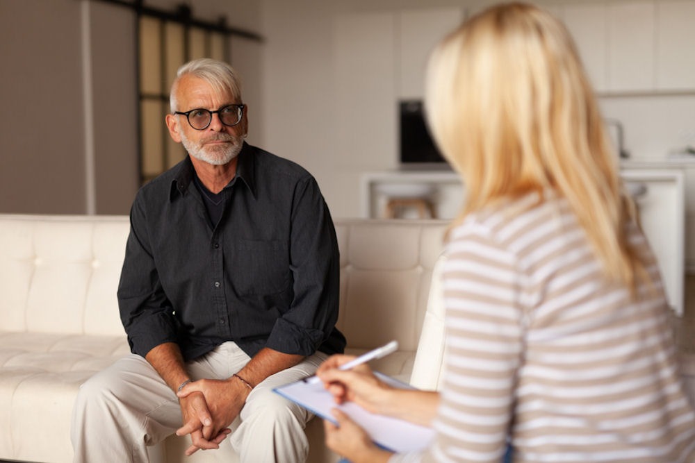 Older man discussing symptoms of alcohol poisoning with a therapist
