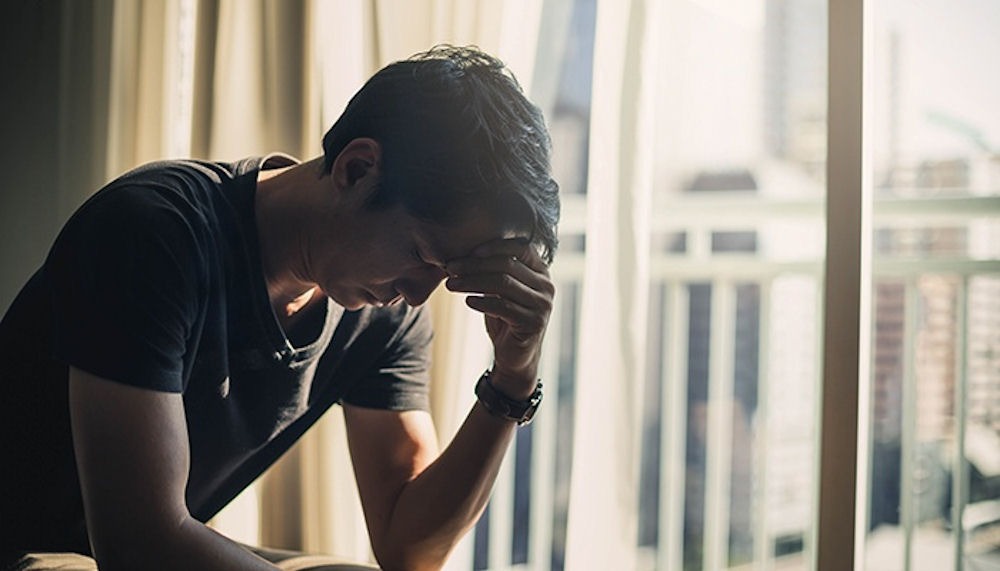 Distressed man holding his head, showing signs of alcohol poisoning