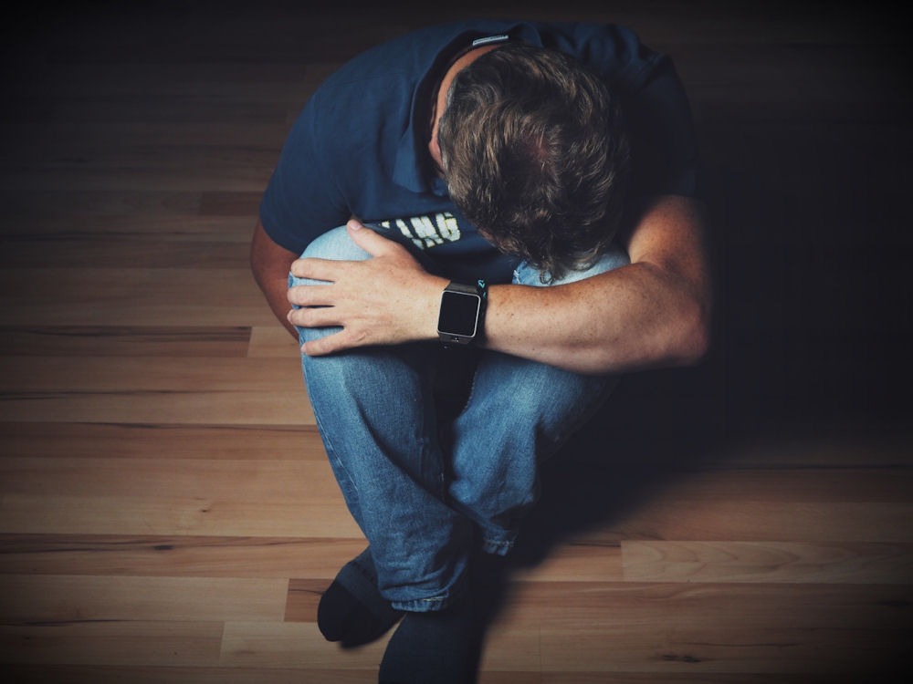 Person sitting on the floor with head down, showing emotional struggle often linked to ambien side effects.