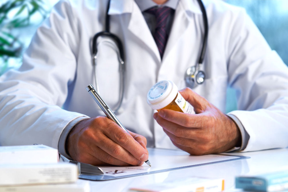 male doctor writes prescription for patient amid doctor shopping concerns